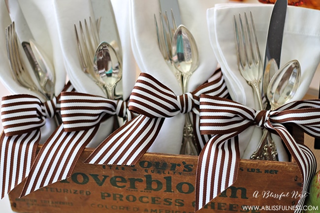 A simple way to dress up your table is by wrapping linen napkins with ribbons and placing in a vintage cheese box. A little glam meets rustic!