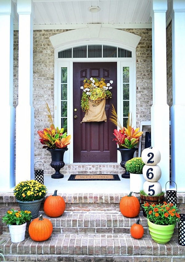 10 Fall Front Porch Decorating Ideas by A Blissful Nest - This front porch fall decor uses bright colors and creative pumpkins with house numbers to create a welcoming fall porch display. 