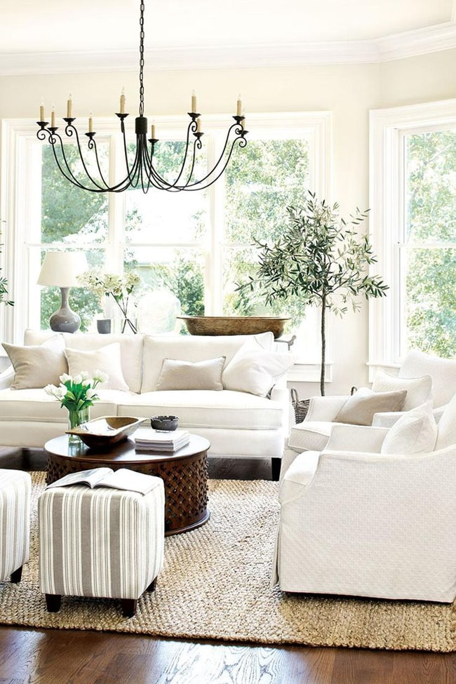 How to decorate with neutral colors: Who said neutral had to be boring? This all-white furniture looks amazing against those large windows filled with green. The pops of color throughout make it feel fresh and clean. 