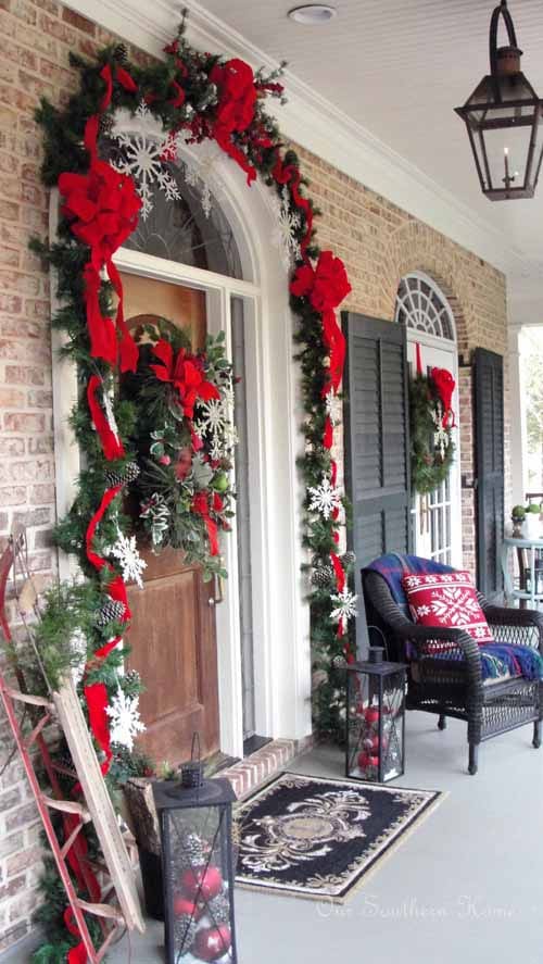 Our Southern Home Christmas Porch, Snowflakes, Garland, Red Bows, Ornaments in Lanterns - Christmas porch ideas from A Blissful Nest