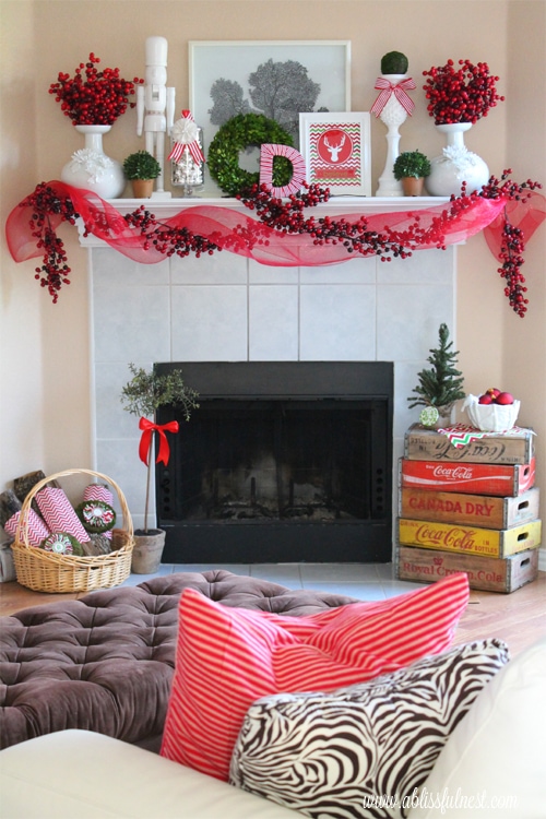 Christmas Mantels - white tile with red holly berry garland, red and green flower accents and red ribbon - Our Christmas Mantel A Blissful Nest