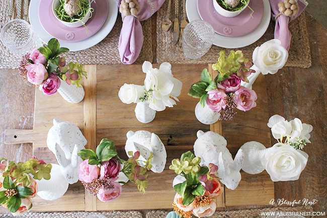 A beautiful and soft Easter table decor setting that is the perfect transition into spring. Soft whites with pops of flowers and pastels makes this Easter table setting perfect for your family! Check out more of this table on ablissfulnest.com