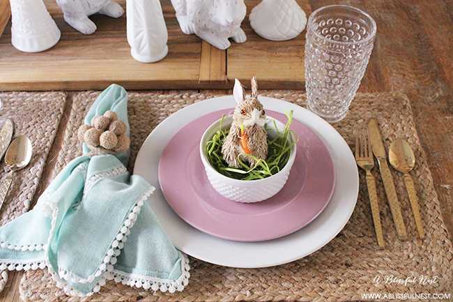 A beautiful and soft Easter table decor setting that is the perfect transition into spring. Soft whites with pops of flowers and pastels makes this Easter table setting perfect for your family! Check out more of this table on ablissfulnest.com