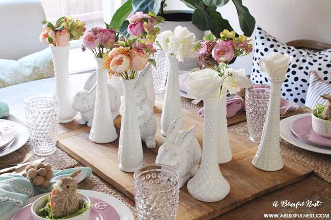 A beautiful and soft Easter table decor setting that is the perfect transition into spring. Soft whites with pops of flowers and pastels makes this Easter table setting perfect for your family! Check out more of this table on ablissfulnest.com