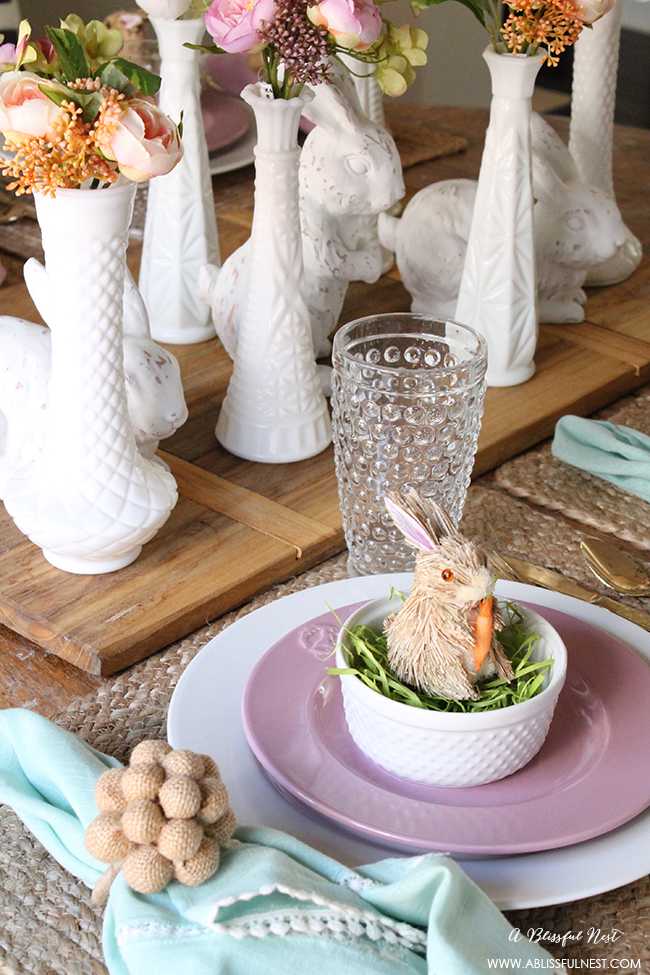 A beautiful and soft Easter table decor setting that is the perfect transition into spring. Soft whites with pops of flowers and pastels makes this Easter table setting perfect for your family! Check out more of this table on ablissfulnest.com