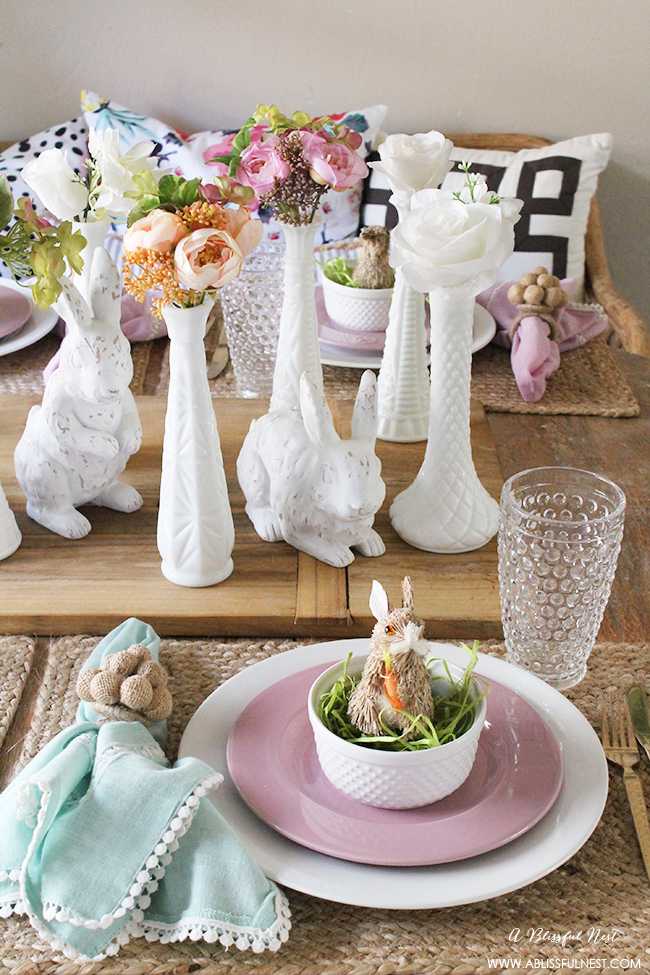 A beautiful and soft Easter table decor setting that is the perfect transition into spring. Soft whites with pops of flowers and pastels makes this Easter table setting perfect for your family! Check out more of this table on ablissfulnest.com