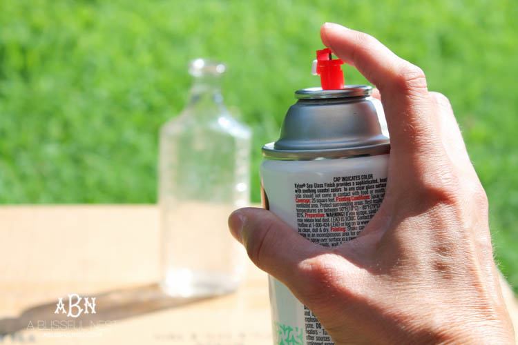 Such an easy tutorial on how to create DIY sea glass bottles using spray paint. Literally 2 steps to get this coastal décor look! See how on https://ablissfulnest.com/ #coastaldecorating #seaglassbottle #designtips #howtomake #diyseaglassbottles