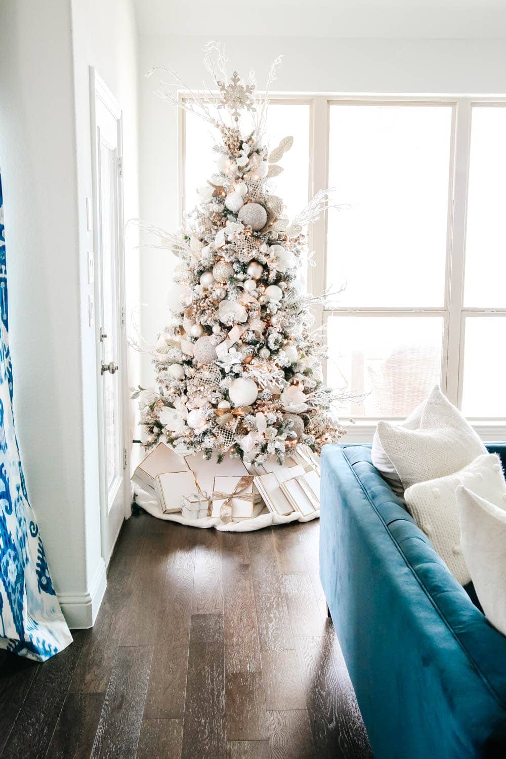 White flocked Christmas tree decorated with silver and gold ornaments.