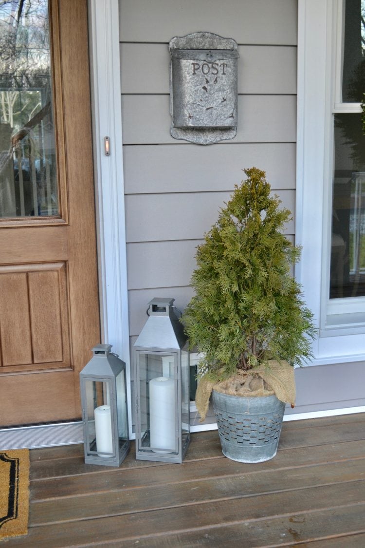 These simple porch decorations are the easiest way to refresh your home in the new year. Silver lanterns with a mini spruce bushell really complete the look!