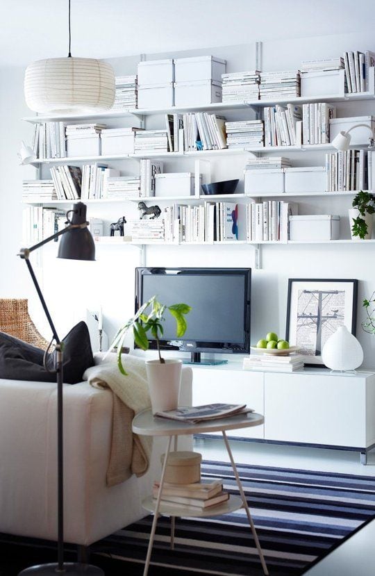 Decorating around a TV is easy when using bookshelves like this TV surrounded by stacks of white books on floating bookshelves