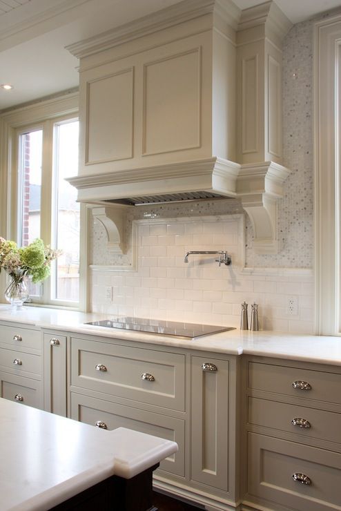 Greige tan colored cabinets with silver cup pulls and a white marble countertop.