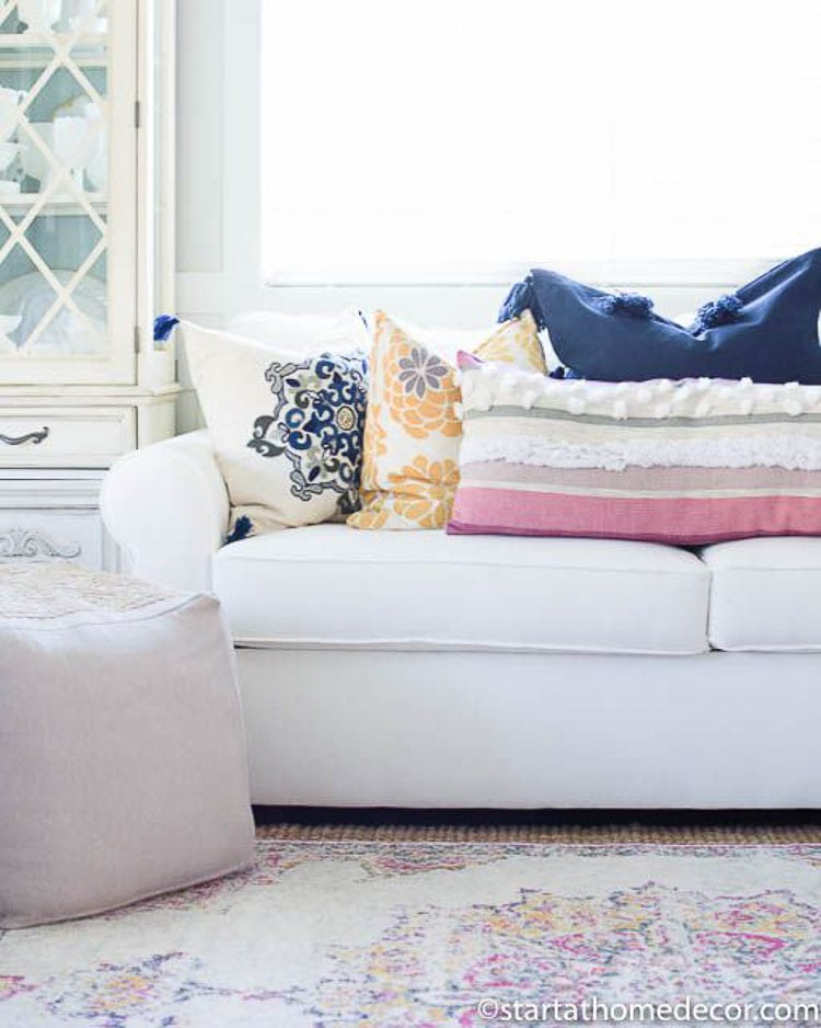 Mixing different patterns and textures of throw pillows is great if you find one element, like complimenting colors to bring the look together like this white couch styled with four different throw pillows