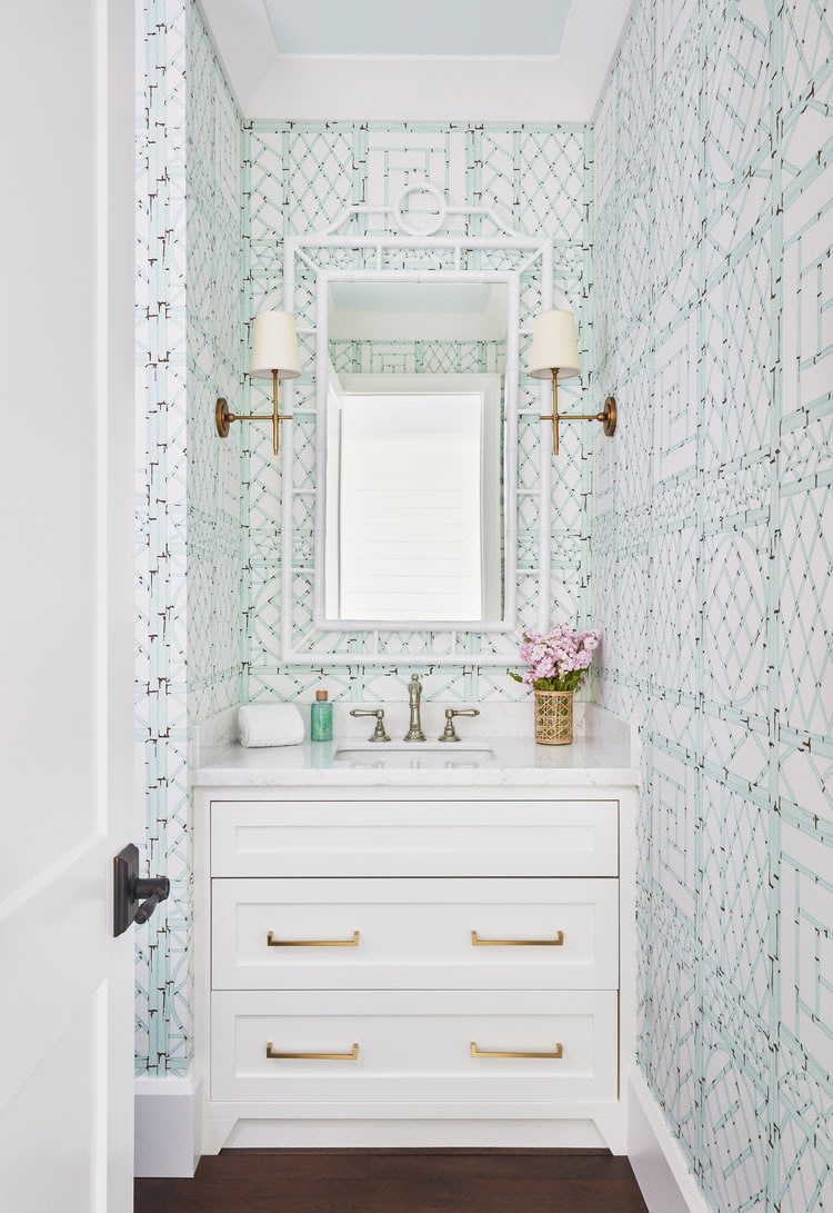 Turquoise patterned wallpaper in a powder bathroom with a white vanity cabinet.