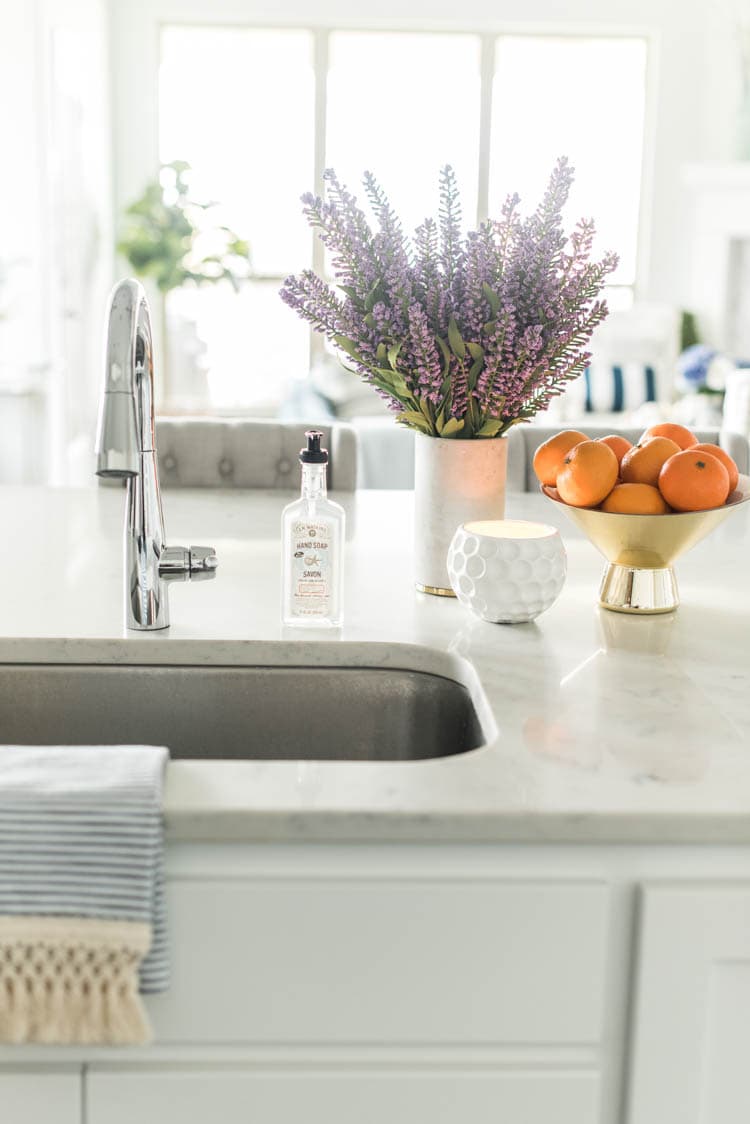Spring touches are easy to add to a kitchen with accessories like a bowl full of oranges and faux flowers. #ad #AthomeStores #springdecorating #springdecoratingideas #kitchen #springkitchen #whitekitchen