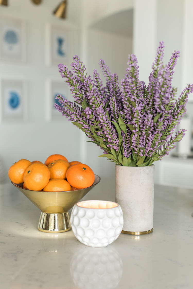 Spring touches are easy to add to a kitchen with accessories like a bowl full of oranges and faux flowers. #ad #AthomeStores #springdecorating #springdecoratingideas #kitchen #springkitchen #whitekitchen