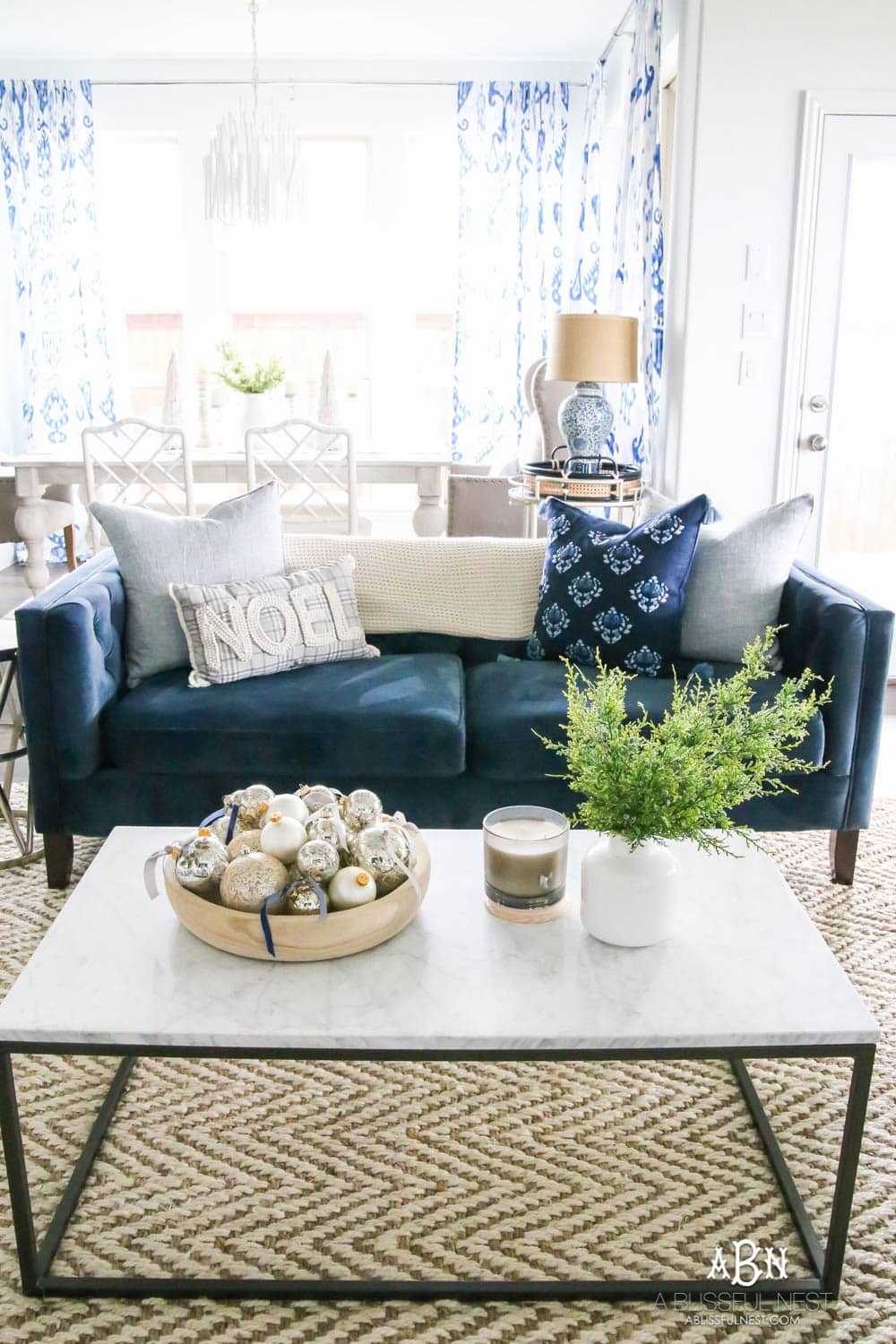 Beautiful blue and silver Christmas living room decor in a bright white space with juniper garland and silver and blush ornaments. Check out all the white, silver and gold Christmas decor in this holiday home tour on ABlissfulNest.com. #ABlissfulNest #Christmasdecor #Christmasdecorating #CoastalChristmasdecor #christmastree #christmasmantle