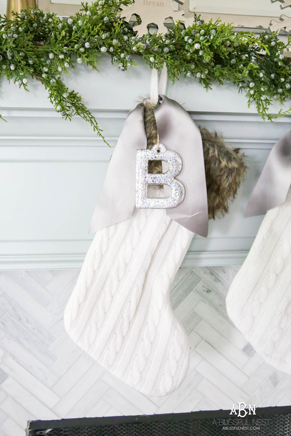 Gorgeous blue and silver Christmas mantle décor with juniper berry garland and glass hurricane Christmas trees. Simple and festive holiday décor in this open concept living space. Check out all the white, silver and gold Christmas decor in this holiday home tour on ABlissfulNest.com. #ABlissfulNest #Christmasdecor #Christmasdecorating #CoastalChristmasdecor #christmastree #christmasmantle