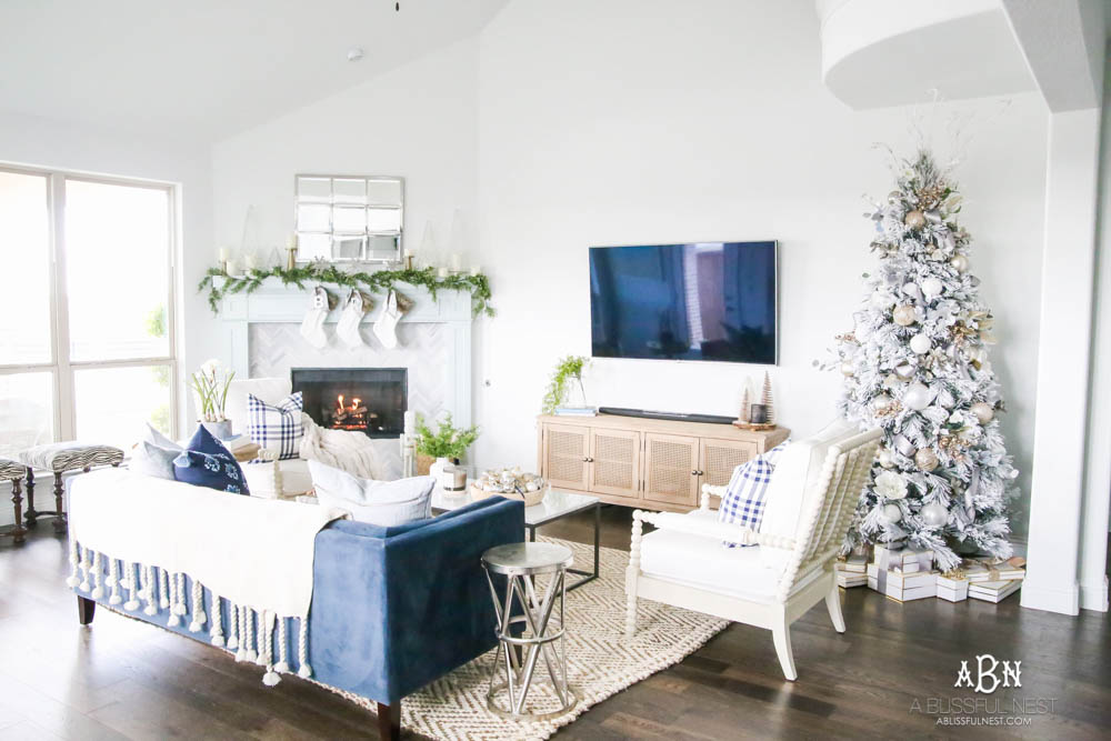 Beautiful blue and silver Christmas living room decor in a bright white space with juniper garland and silver and blush ornaments. Check out all the white, silver and gold Christmas decor in this holiday home tour on ABlissfulNest.com. #ABlissfulNest #Christmasdecor #Christmasdecorating #CoastalChristmasdecor #christmastree #christmasmantle