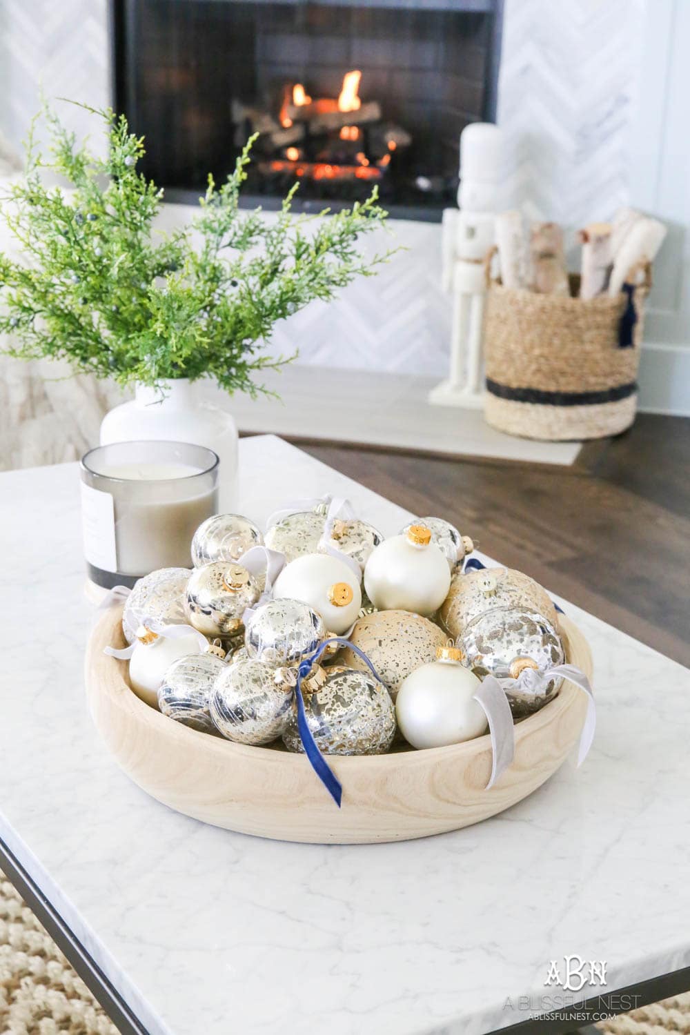 Mercury glass ornaments with velvet ribbons tied and collected in a wood bowl on a coffee table for a gorgeous holiday décor display. Simple touches for Christmas décor that make big impact. Check out all the white, silver and gold Christmas decor in this holiday home tour on ABlissfulNest.com. #ABlissfulNest #Christmasdecor #Christmasdecorating #CoastalChristmasdecor #christmastree #christmasmantle