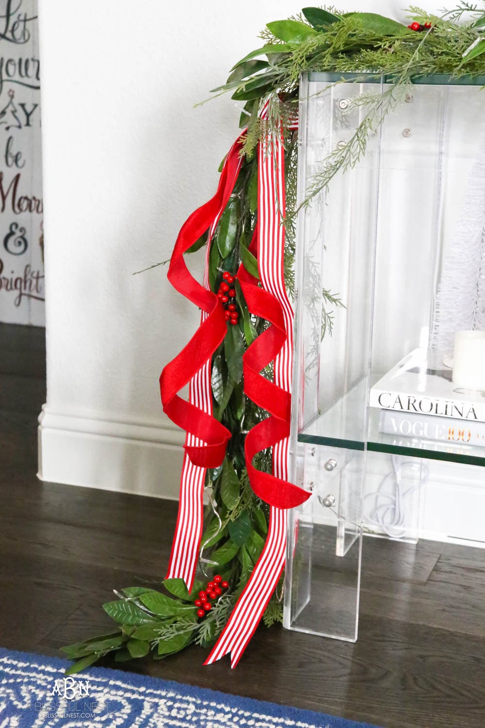 Layered garland makes a full look and adding in festive red and white ribbon. Love these easy and simple classic Christmas touches in this entryway. #christmasentryway #christmasentry #christmasentrydecor #christmasentrywayideas #christmashometour