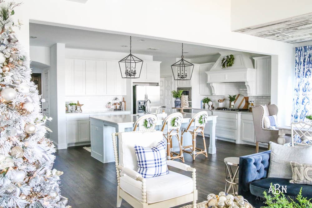 Blue and silver Christmas kitchen décor. All white kitchen with subtle holiday décor for a fresh coastal Christmas look. Mini wreaths on the backs of the barstools, beautiful bay leaf above the range. #christmaskitchen #christmashometour #holidayhometour #kitchenideas