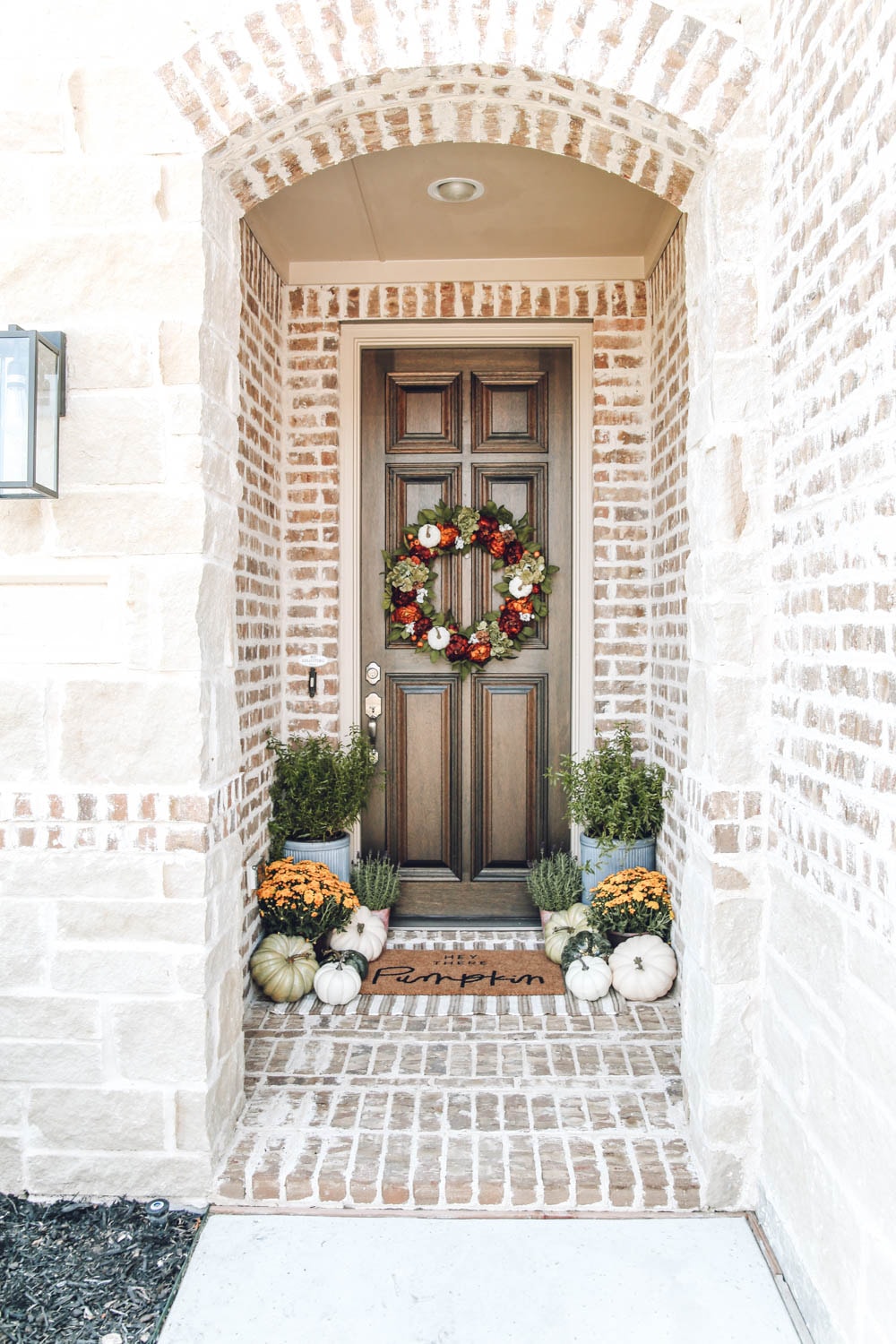 Autumn colors in this fall front porch. mums, pumpkins, hey there pumpkin door matt mixed with burnt orange, muted greens and touches of golden yellow. #ABlissfulNest #fallporch #falldecor #fallinspiration