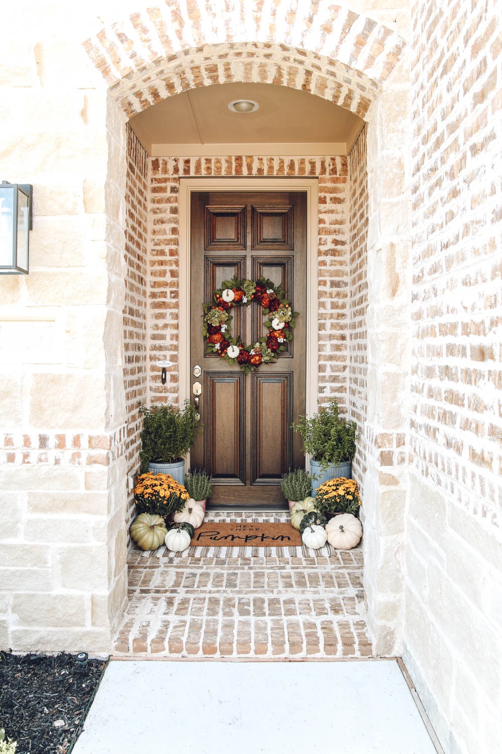 Autumn colors in this fall front porch. mums, pumpkins, hey there pumpkin door matt mixed with burnt orange, muted greens and touches of golden yellow. #ABlissfulNest #fallporch #falldecor #fallinspiration