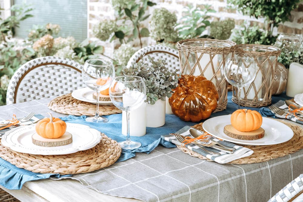 Blue and orange fall table decor. Mini orange pumpkins, white plates, lanterns and candles. #ABlissfulNest #fallinspiration #falldecor #Thanksgiving