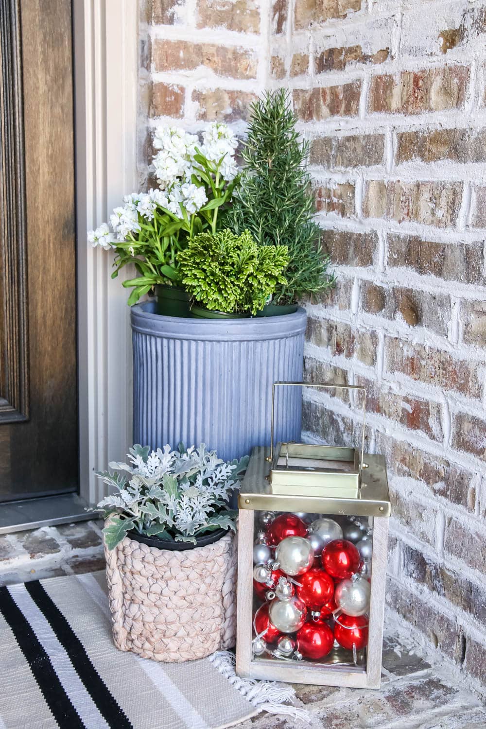 Gold lantern filled with Christmas ornaments, fresh winter flowers and a striped doormat. #ABlissfulNest #christmasporch #christmasdecor