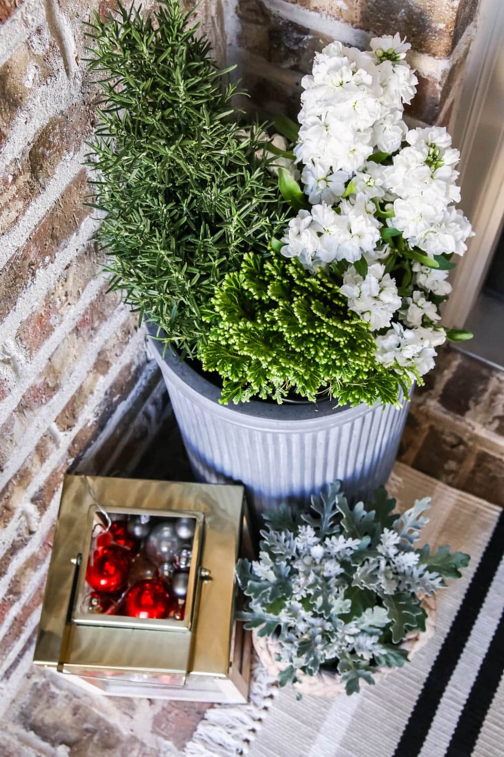 Gold lantern filled with Christmas ornaments, fresh winter flowers and a striped doormat. #ABlissfulNest #christmasporch #christmasdecor