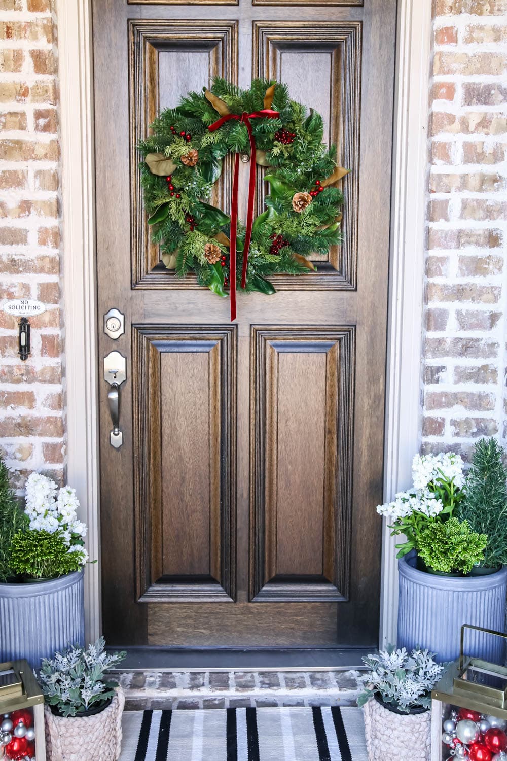 A traditional Christmas porch in red and green with gold lanterns, Christmas ornaments and fresh flowers. #ABlissfulNest #christmasporch #christmasdecorating