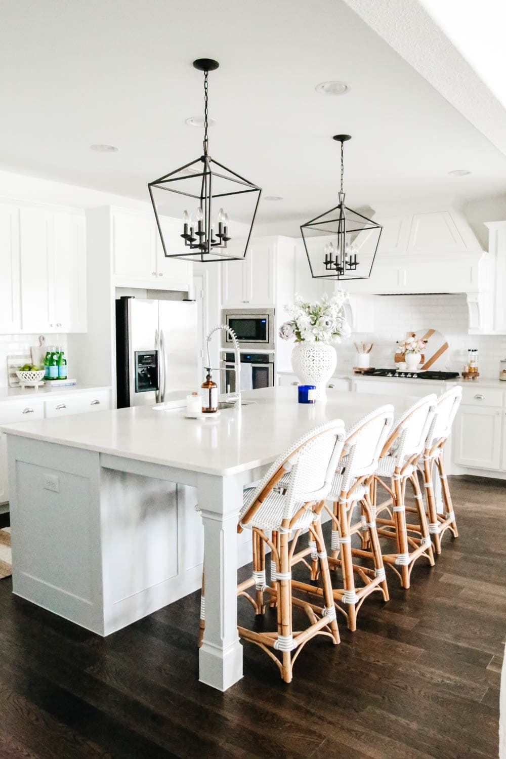 White kitchen with blue painted island. Rattan bistro chairs, black lanterns, carrara quartz counters. #ABlissfulNest #whitekitchen #springhometour