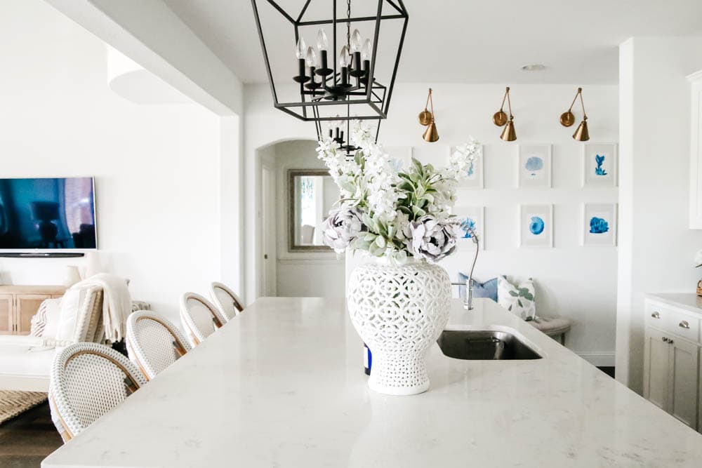 White kitchen with blue painted island. Rattan bistro chairs, black lanterns, carrara quartz counters. #ABlissfulNest #whitekitchen #springhometour