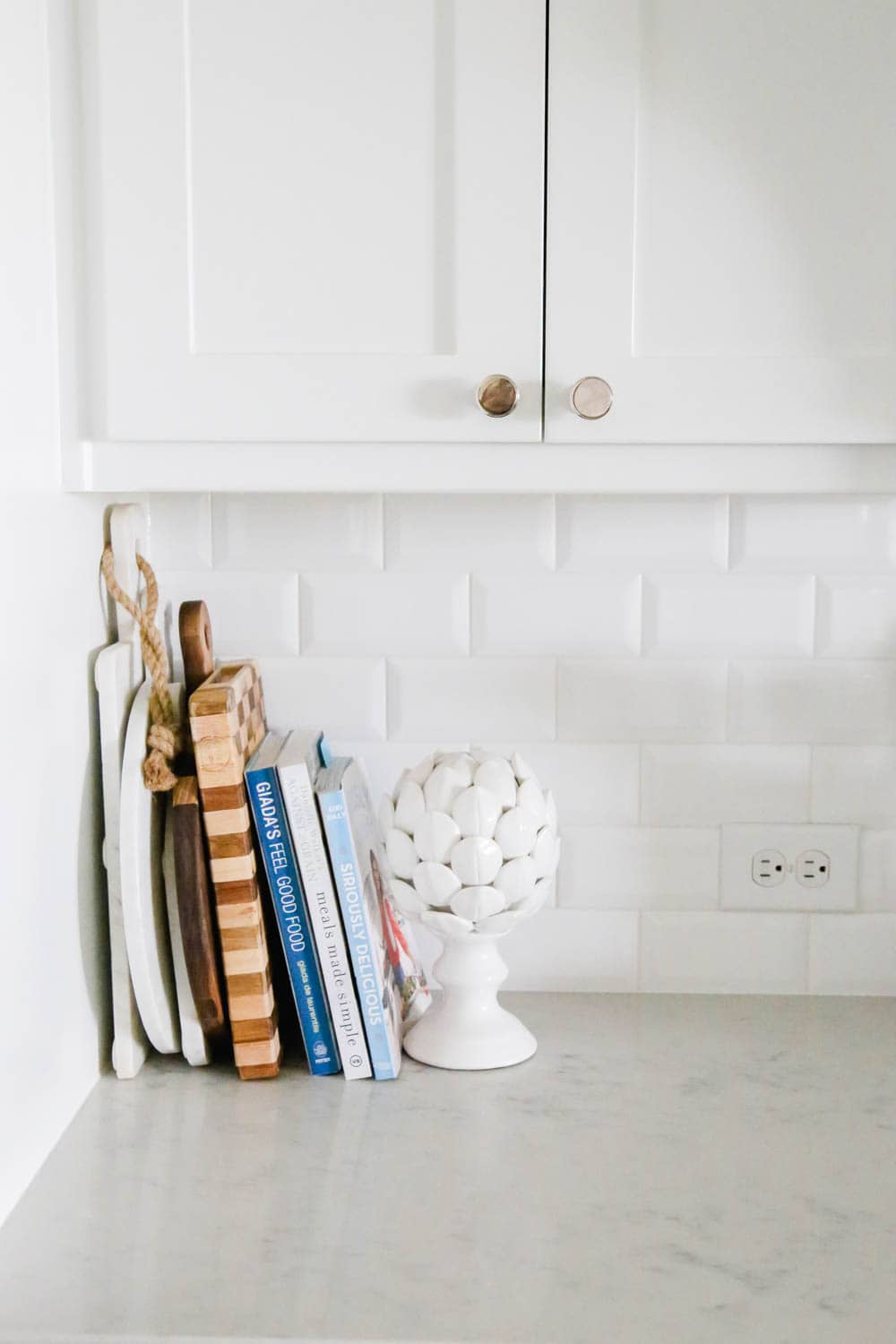 Kitchen counter decorating with cookbooks and cutting boards. #whitekitchen #kitcheninspo #kitchendecor #ABlissfulNest