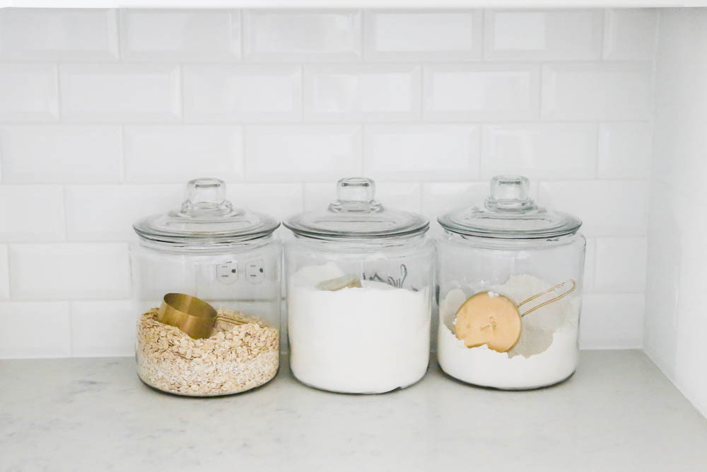 Glass canisters to hold baking essentials with gold measuring cups. #whitekitchen #kitcheninspo #kitchendecor #ABlissfulNest