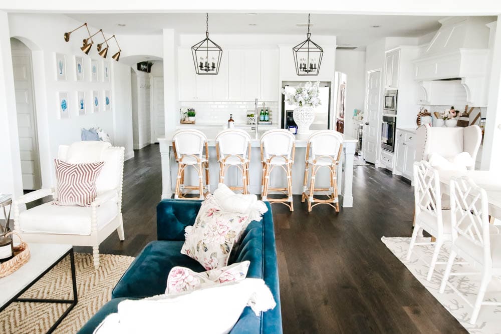 Bright white walls with blue home decor, navy velvet sofa, french bistro barstools, white kitchen with soft texture accents. #ABlissfulNest #whitekitchen #whiteinterior #designtips #kitchen