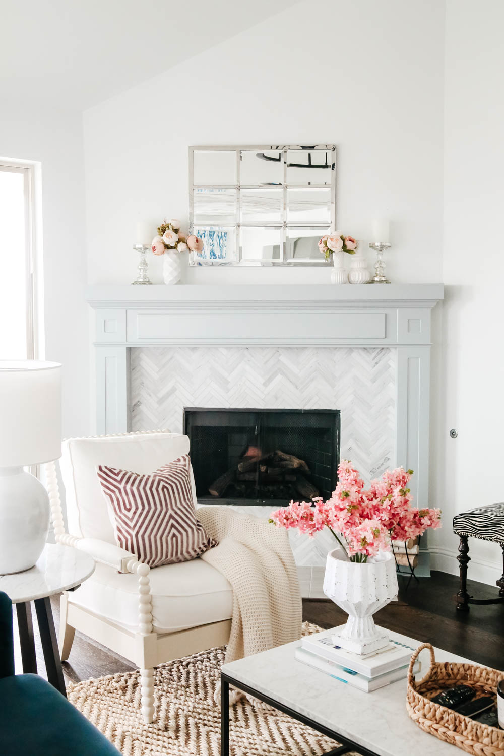 Light grey blue painted fireplace mantle with white spindle chair and lavender home decor accents. #livingroominspo #hometour #fireplacemantle #springhometour #ABlissfulNest