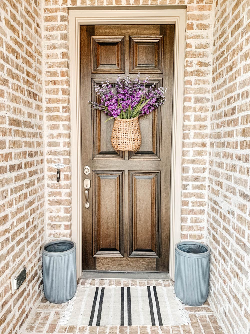 Tall grey fluted planters, tan and black striped doormat