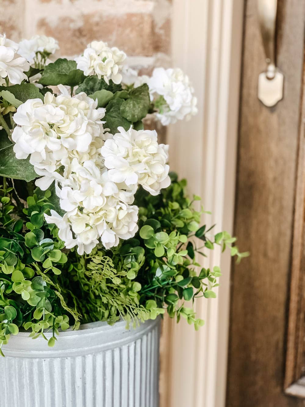 Mix of maidenhair ferns and faux boxwoods in a planter