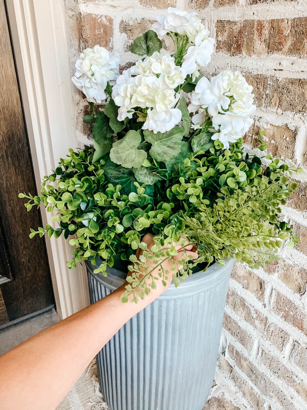 Placing maidenhair fern stems into the open areas of the planter.