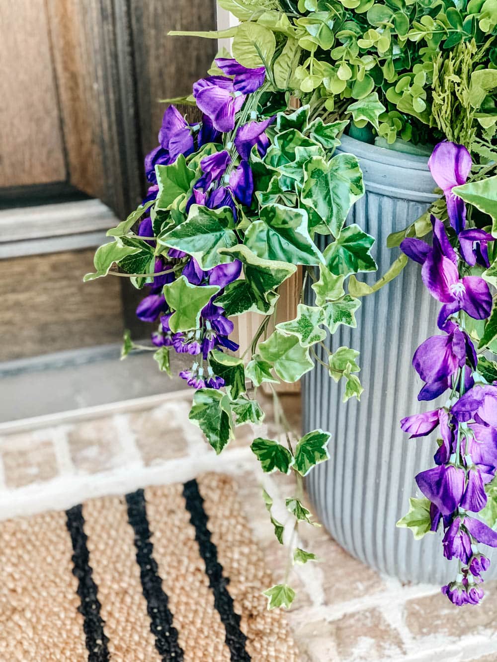 Faux purple flowers cascading over the edge of the planter.