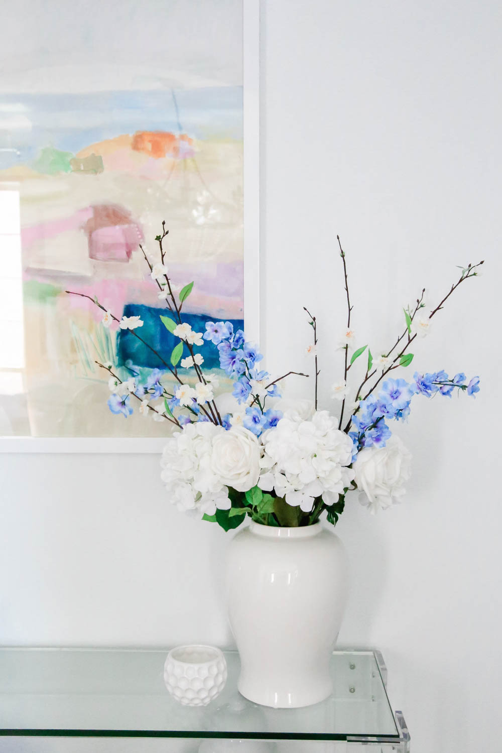 Simple faux flowers in blue and white add a summery touch to this entryway table. #entryway #summerdecor #ABlissfulNest
