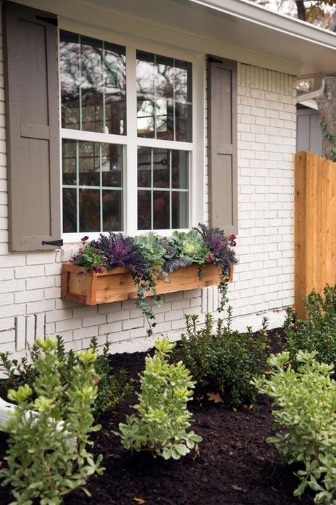 wood window box planter filled with cabbage, and other greenery that adds a garden feel. Light brown shutters on cream painted brick exterior.