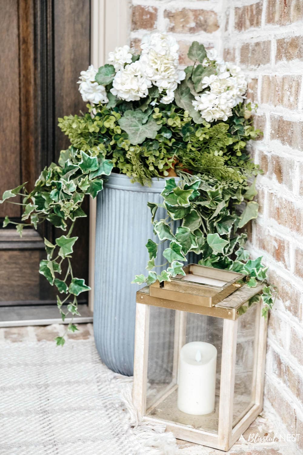 A simple fresh summer porch includes this beautiful hoop wreath, UV protected outdoor faux flowers, lanterns and more. #ABlissfulNest #summerporch #summerdecor