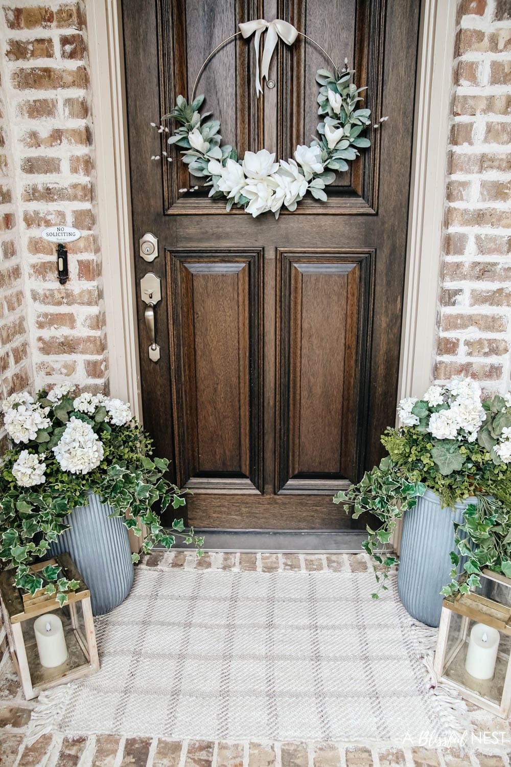 A simple fresh summer porch includes this beautiful hoop wreath, UV protected outdoor faux flowers, lanterns and more. #ABlissfulNest #summerporch #summerdecor