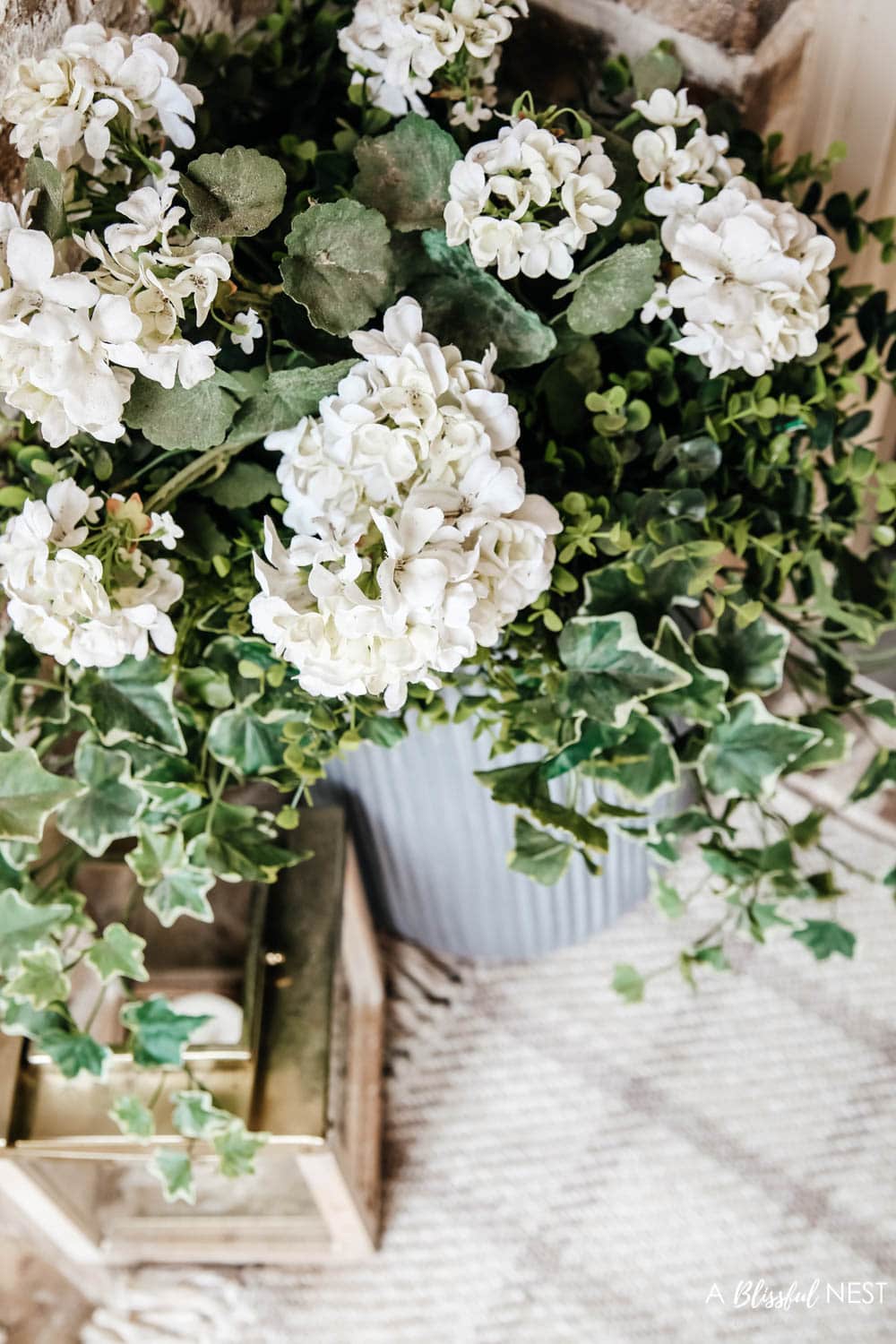 A simple fresh summer porch includes this beautiful hoop wreath, UV protected outdoor faux flowers, lanterns and more. #ABlissfulNest #summerporch #summerdecor