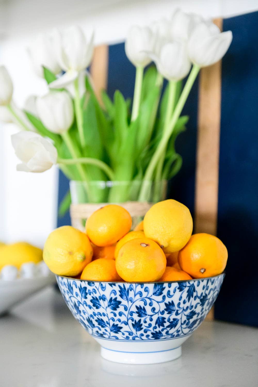 Add a bowl of fruit for color, blue and white bowl, tulips, cutting boards. #ABlissfulNest #kitchendecor #whitekitchen