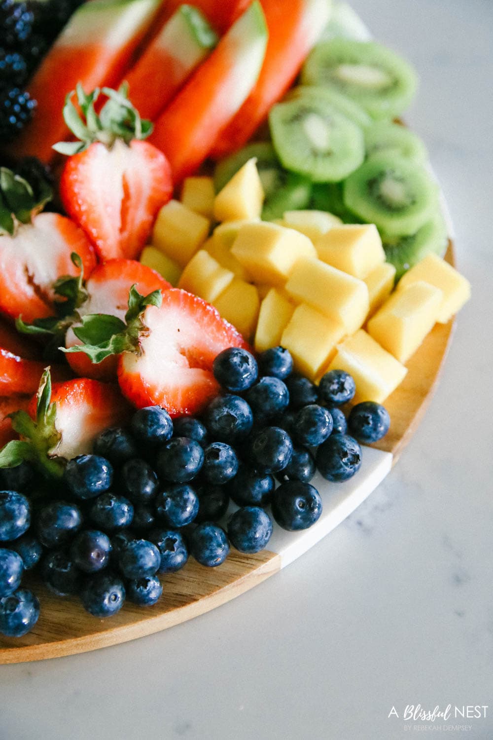 This beautiful fruit charcuterie board is so good to make on the weekends, for brunch, as an appetizer, and use all your favorite colorful fruits. #ABlissfulNest #charcuterieboard #fruitboard #fruitrecipe