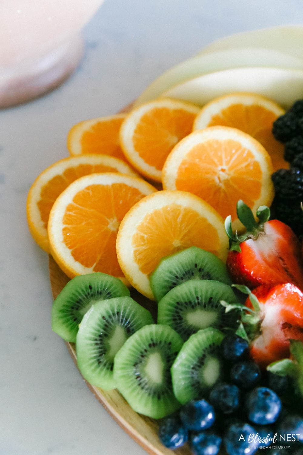 This beautiful fruit charcuterie board is so good to make on the weekends, for brunch, as an appetizer, and use all your favorite colorful fruits. #ABlissfulNest #charcuterieboard #fruitboard #fruitrecipe