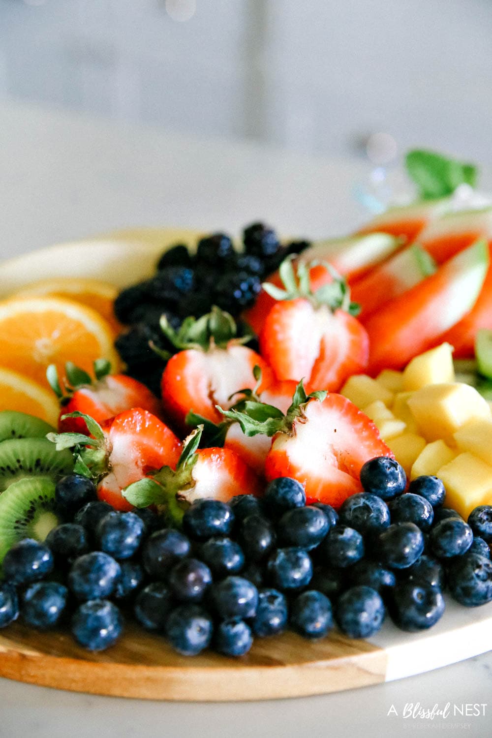 This beautiful fruit charcuterie board is so good to make on the weekends, for brunch, as an appetizer, and use all your favorite colorful fruits. #ABlissfulNest #charcuterieboard #fruitboard #fruitrecipe